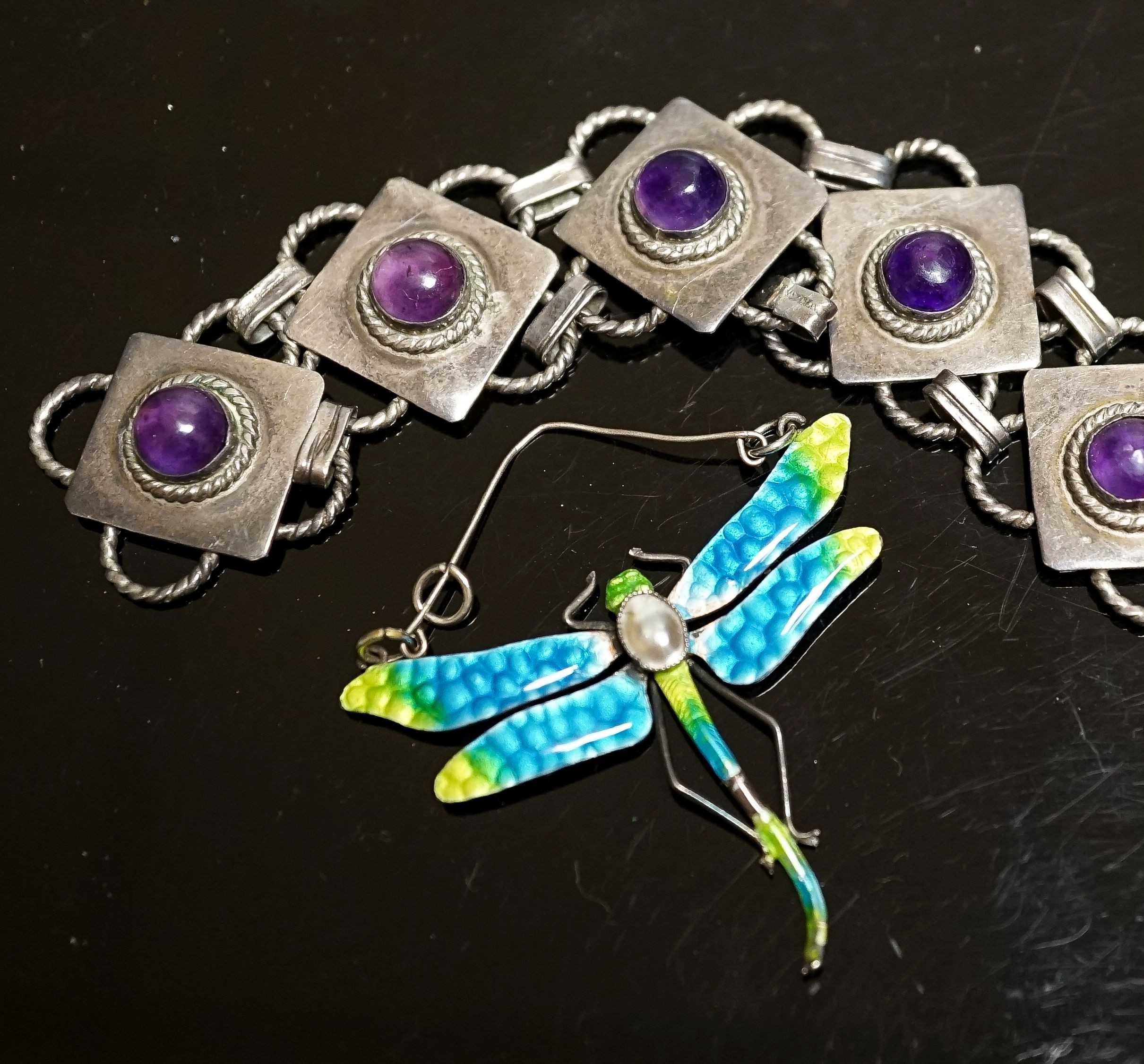 A white metal and seven stone cabochon amethyst set bracelet, 18.5cm and a white metal, mother of pear, and enamel set dragonfly pendant(a.f.), diameter 47mm.